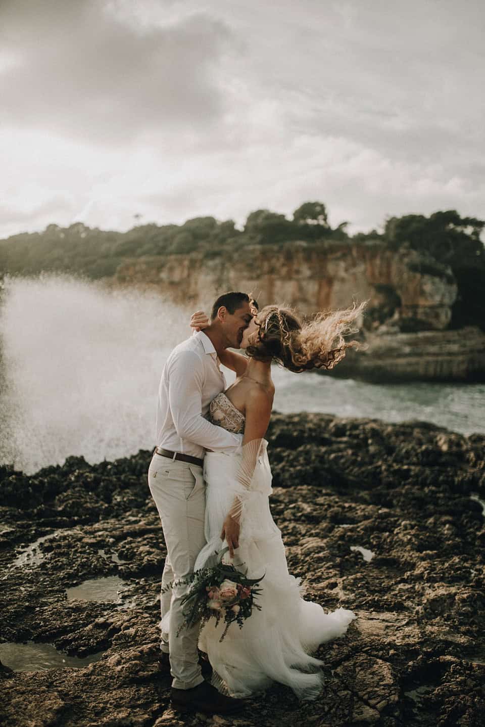 Tanzendes Hochzeitspaar am Meeresufer bei Sonnenuntergang, romantische Hochzeitsfotografie in Tirol, Österreich.