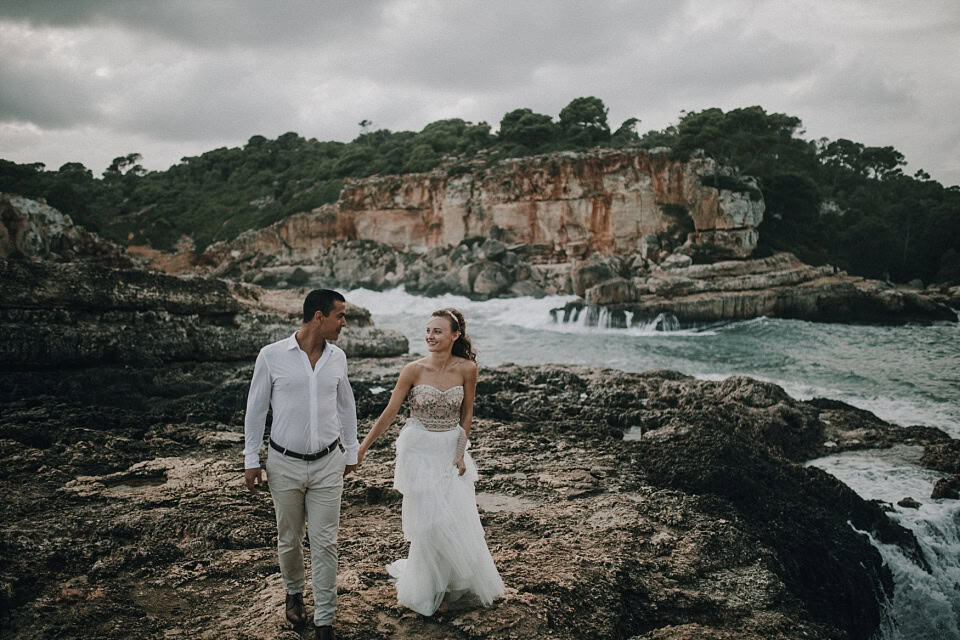 Romantisches Brautpaar am Strand bei bewölktem Himmel, Hochzeitsfotografie an der Küste, natürliche Hochzeitsmomente, Tirol Österreich international.