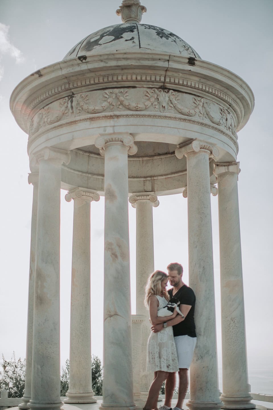 Romantisches Paar unter klassischer Tempelruine bei Sonnenuntergang, ideal für Hochzeitsfotografie in Tirol.