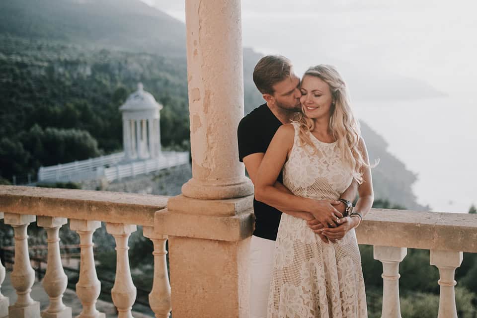 Romantisches Hochzeitsfoto auf einer Terrasse mit Blick aufs Meer, Braut und Bräutigam umarmend, in Tirol aufgenommen.