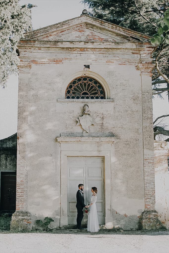 Zeitloser Hochzeitsmoment vor einem alten, charmanten Kirchengebäude in Tirol, Österreich.