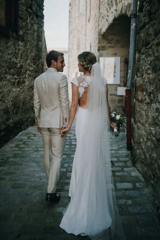 Hochzeitsfotograf Tirol - Braut und Bräutigam Hand in Hand in alter Gasse, emotionale Hochzeitsfotos, authentischer Moment, romantisches Paarshooting.