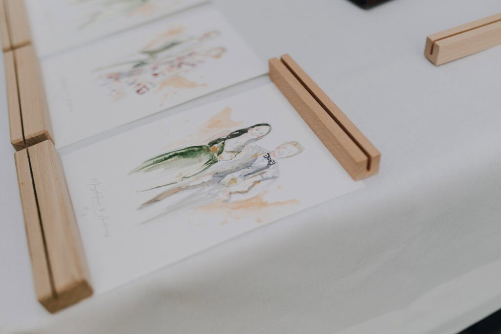 Aquarellzeichnung eines Brautpaares in einem Holzaufsteller. Hochzeit München.