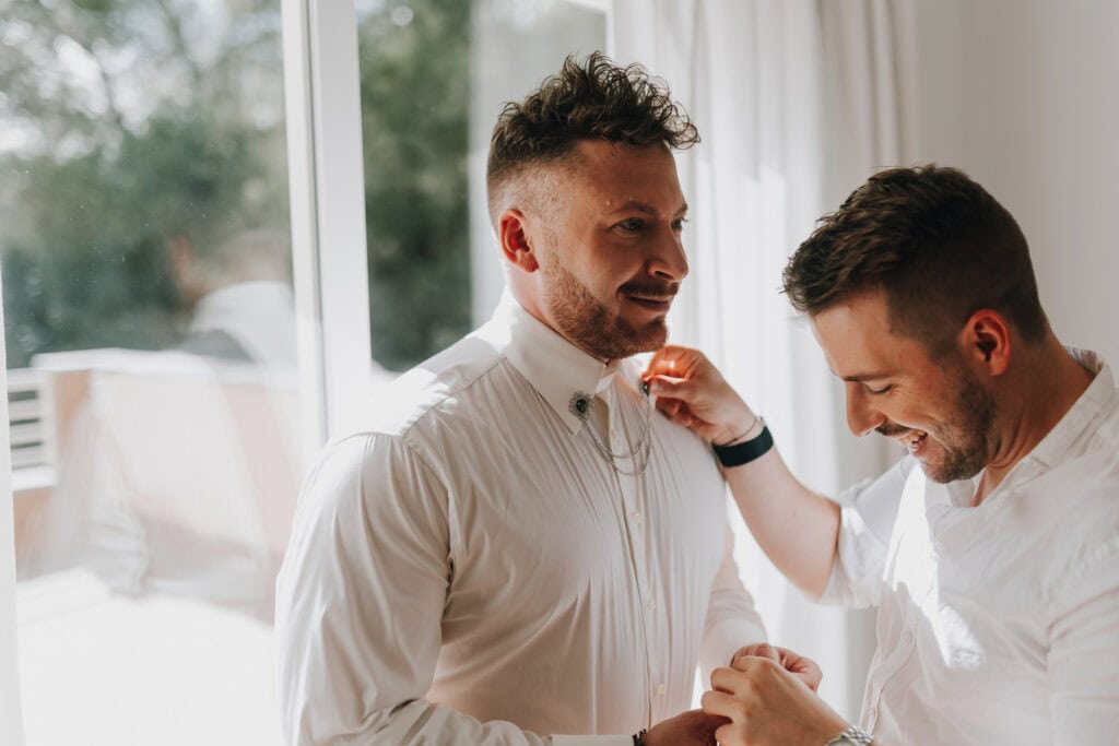 Bräutigam wird von Freund am Hochzeitstag geholfen. Vorbereitung für Hochzeit auf Ibiza.