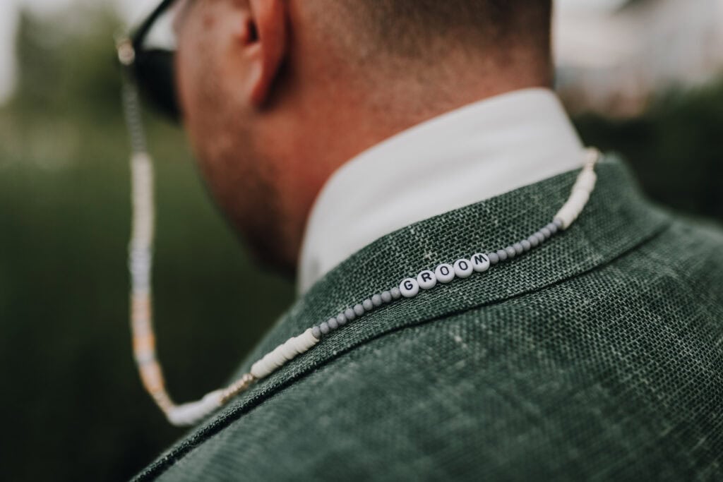 Bräutigam mit Perlenkette "GROOM" auf grünem Sakko. Hochzeit in München.