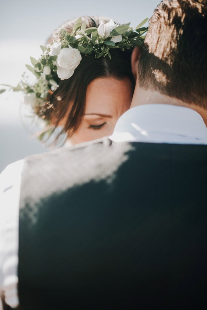Braut mit Blumenkranz umarmt Bräutigam. Romantische Hochzeit in Irland.