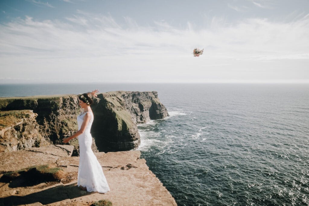 Braut wirft Brautstrauß an den Cliffs of Moher, Irland. Hochzeitsfotograf Irland.