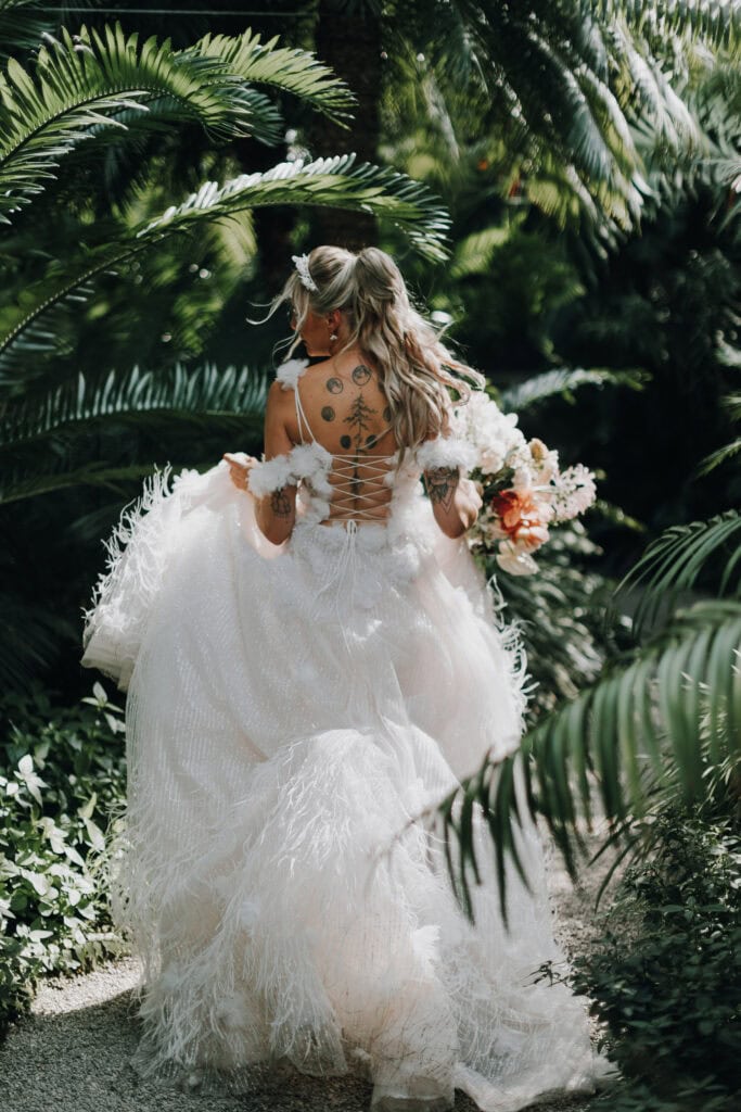 Braut mit Tattoo und üppigem Kleid im Garten, Hochzeit München.