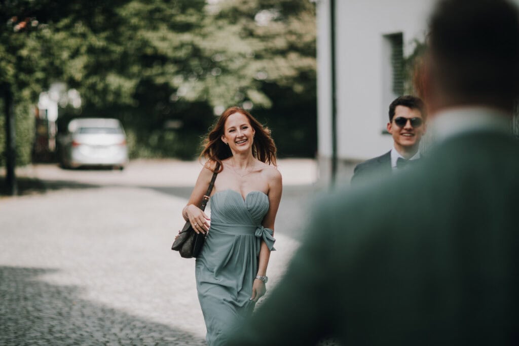 Fröhliche Brautjungfer im mintgrünen Kleid auf dem Weg zur Hochzeit in München.