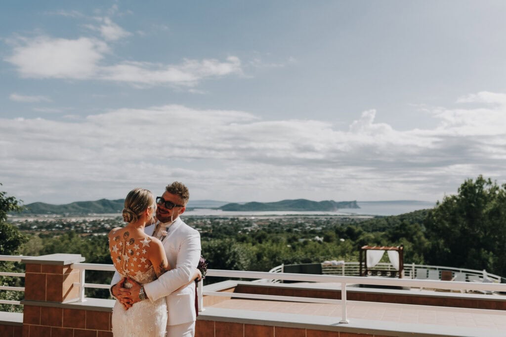 Brautpaar umarmt sich auf Ibiza mit Meerblick. 