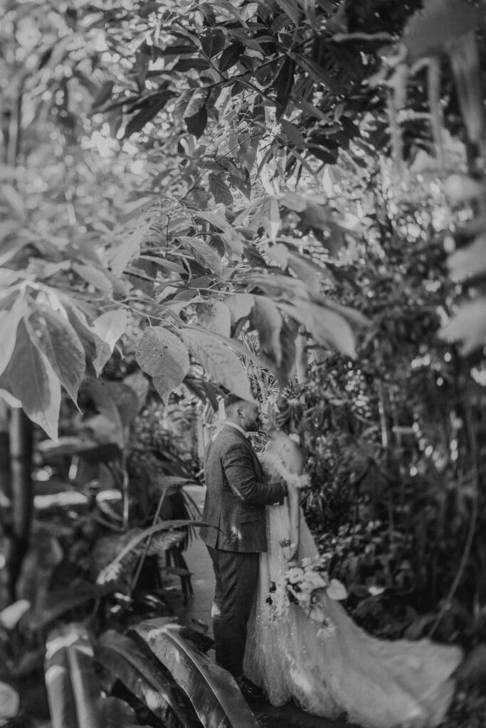 Romantisches Hochzeitsfoto: Brautpaar umarmt sich inmitten üppiger, grüner Natur. München Hochzeitsfotograf.