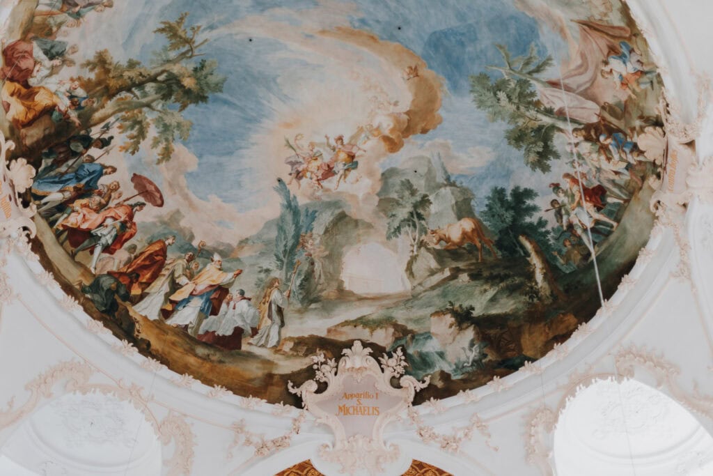 Deckenfresko in der Kirche St. Michaelis, mit religiösen Szenen und Engeln. "Apparitio I. Michaelis" Text.