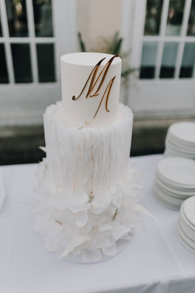 Elegante Hochzeitstorte in Weiß mit goldenem Monogramm "M".