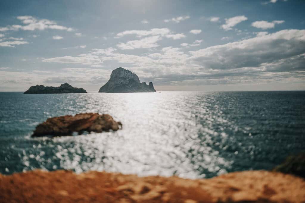 Felsinsel Es Vedrà vor Ibiza im Meer. Bewölkter Himmel, sonniges Wasser.