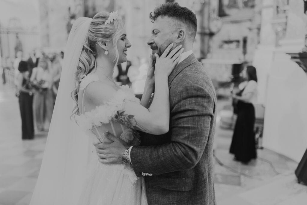 Brautpaar in München umarmt sich liebevoll in Kirche. Hochzeit, Glück, Liebe.