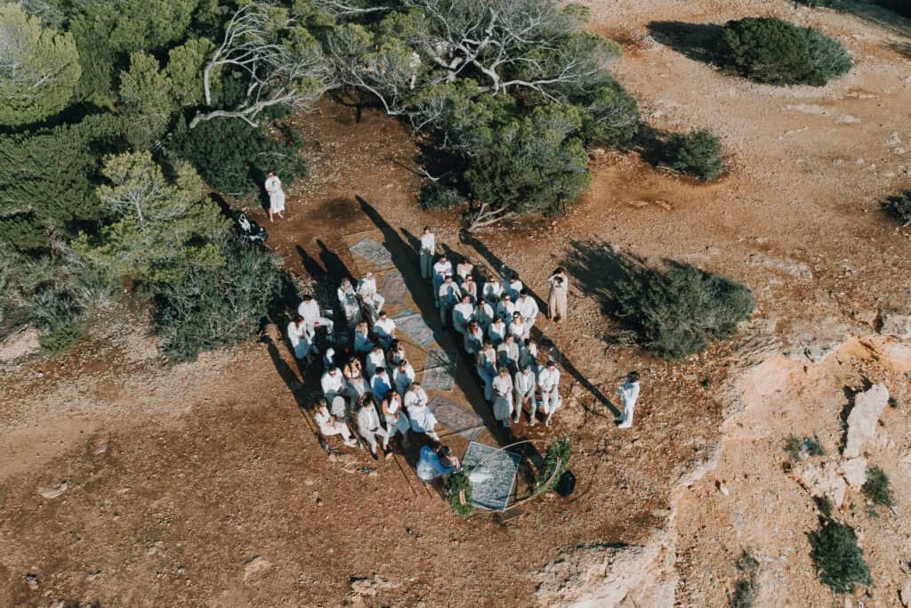Vogelperspektive einer Hochzeitszeremonie im Freien auf Ibiza mit Gästen in Weiß.