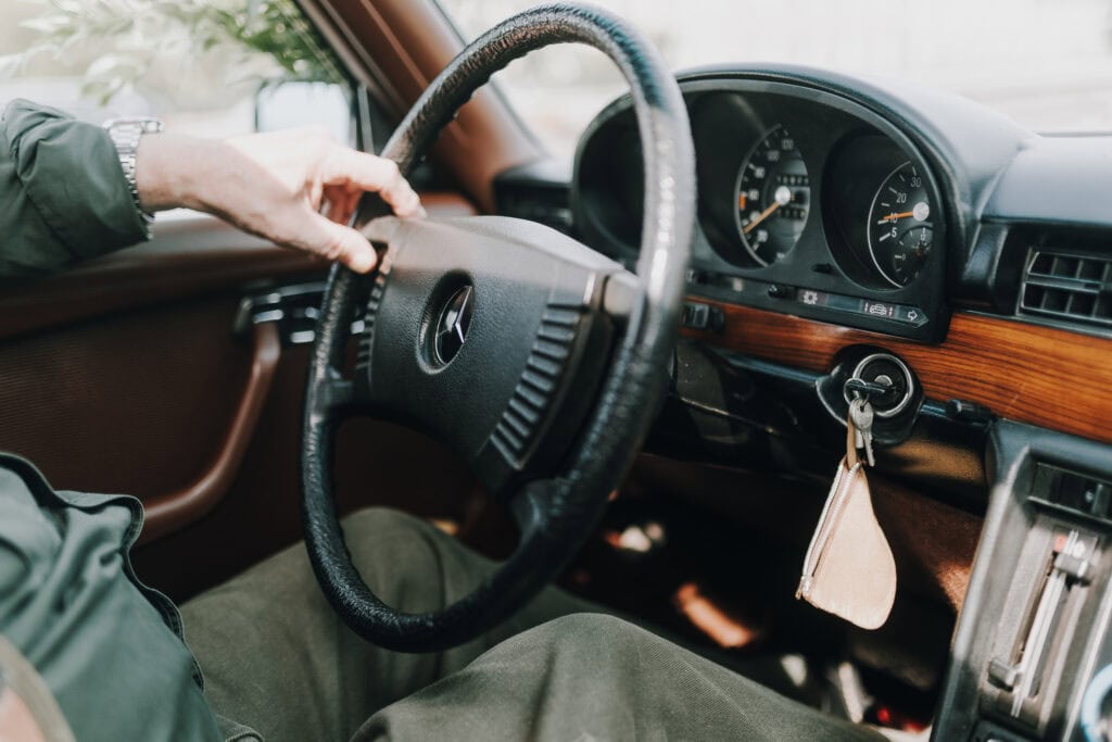 Innenraum eines Mercedes Oldtimers: Lenkrad, Armaturenbrett und Hand des Fahrers. Klassisches Autointerieur.