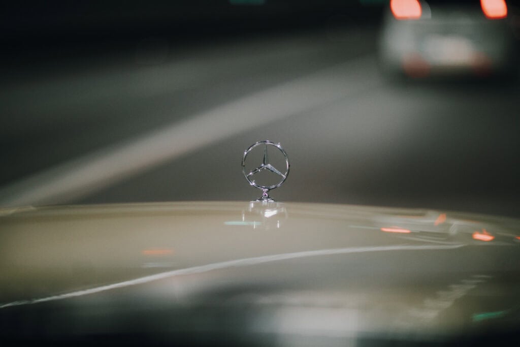 Mercedes-Stern auf Motorhaube, unscharfer Hintergrund. Autofahrt bei Nacht.