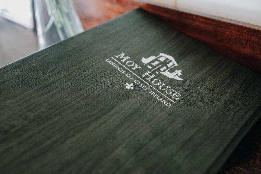 Moy House Menü in Lahinch, Irland. Logo des Hotels auf dunklem Holz. 